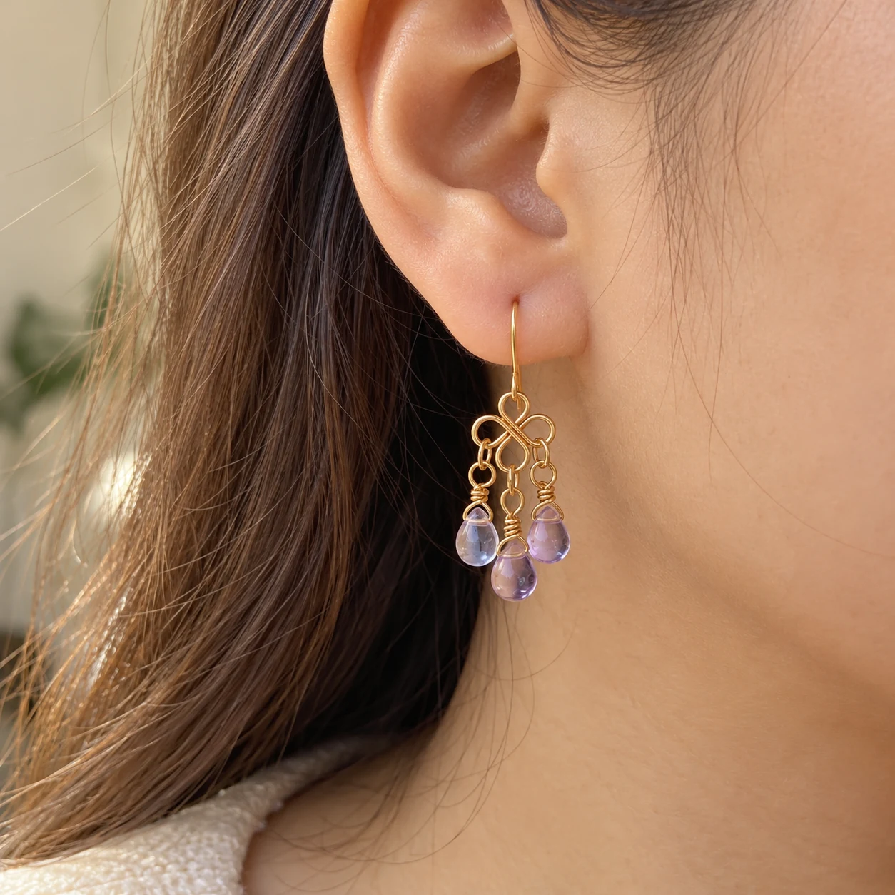 Close-up of an earring with lavender beads being worn